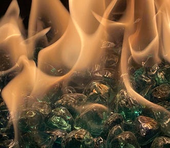 This is a photo of fire over shiny green stones.