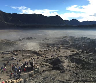 Desert plain with mountains in the background, people walking in a line