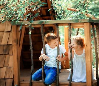 Photo of a boy and a girl up inside their tree house.