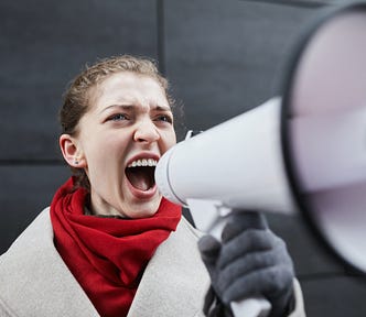 Young, white woman shouting into blow horn.