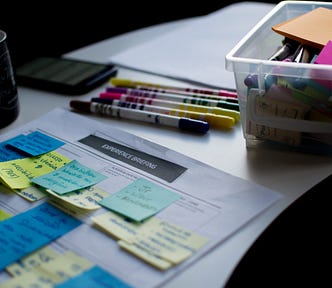 Sticky notes on paper document beside pens and box