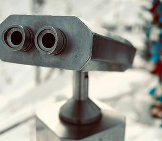 A close-up of a pair of metal, mounted binoculars, which superficially resembles a robot’s face.