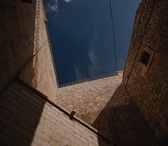 Tall, brown brick building under blue sky.