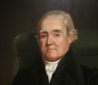 A closeup of the solemn-looking face of an elderly man (Noah Webster) excerpted from a full-color portrait.