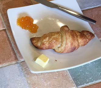 Home-made croissant. on a plate with butter and jam