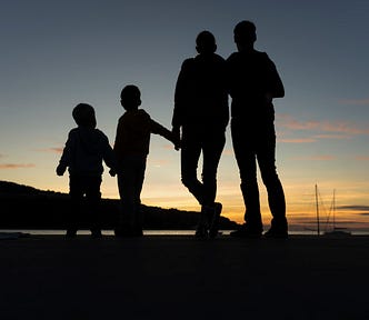 The silhoutte of a family holding hands at sunset.