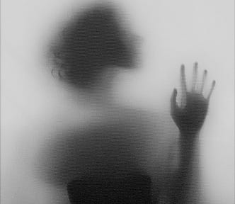 Silhouette of a woman behind a blurry glass.