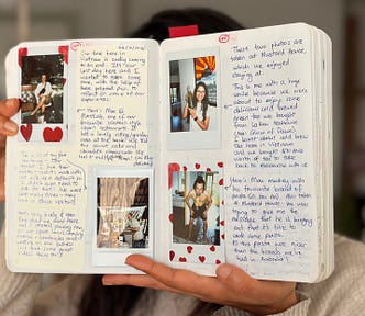 A woman holding up an open book in front of her face. The book shows photographs and handwriting.