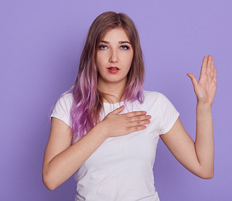 A photo of a young woman with her right hand on her heart and her left hand raised as though making an oath.