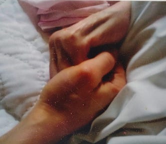 Photo of the author holding her mother’s hand in the latter’s bed