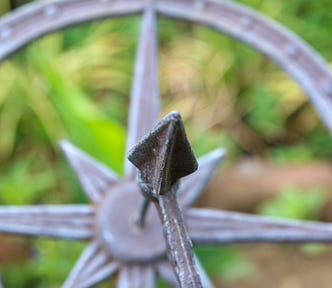 Metal sundial set against background of soft focus greenery.