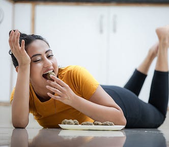 Image of Asian woman eating from a plate as she lounges on the floor