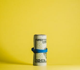A roll of American money on a yellow background.