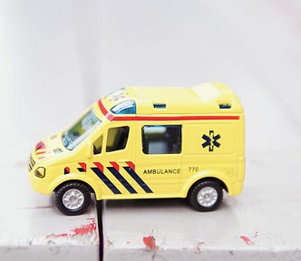 Yellow ambulance toy on white surface