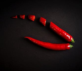 Image of two red chilli peppers, one sliced and one whole