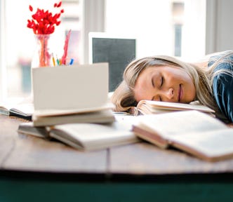 A girl sleeping on her books.