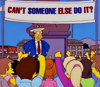 A still from the Simpsons with Homer standing in front of a crowd in front of a sign that says “Can’t someone else do it?”