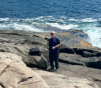 Man with a camera overlooking the ocean.