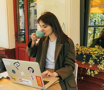 Woman sipping coffee at a coffee shop, working on her computer