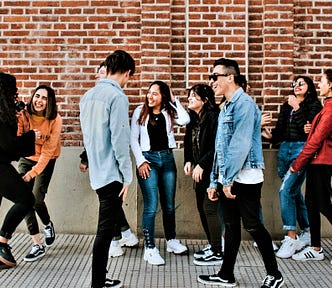 group of people gathered in front of red brick wall talking and smiling