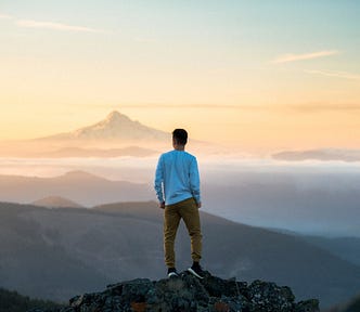 A person standing on a mountain at sunset.