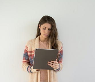 A woman standing while holding a clipboard.