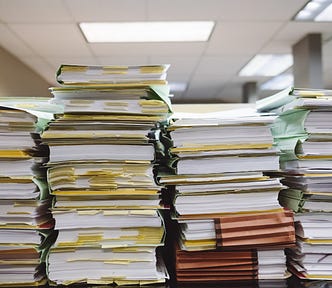 Piles of papers in folders stacked on top of each other.