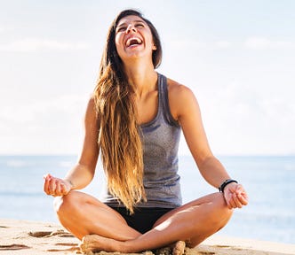 happy smiling girl in lotus pose with ocean in background