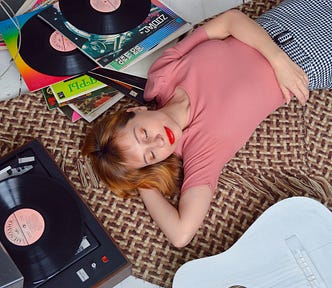 woman lying down with eyes closed listening to vinyl records