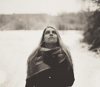 young woman, dressed in coat and scarf, outside in the snow
