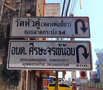 Two signs in Thai script with arrows showing a change in direction