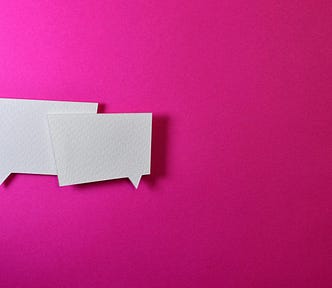 Two square white speech bubbles on a bright pink background.