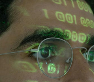 Close-up image of a person with binary code projected onto their glasses.