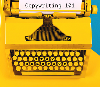 A photo of a yellow typewriter with a sheet of paper with the words “Copywriting 101” typed on it.