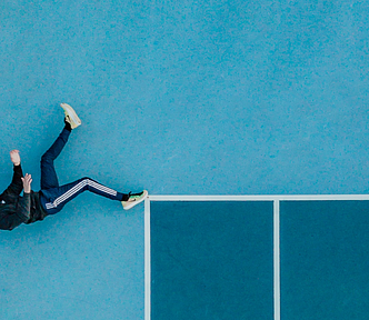 Man lying alone on a tennis court with 3D glasses on