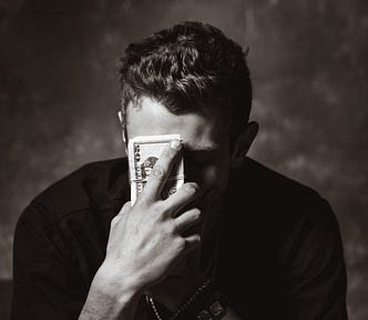 A guy who holds in his hand a pile of dollars and touches his forehead with it