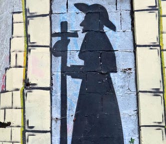Wall art shows a silhouette of St. James, wearing a long robe and a wide-brimmed hat. He holds a staff with a cross at the top and a small bag that is attached