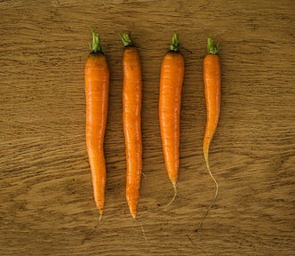 Top down view of four freshly washed carrots on a wooden counter top