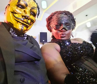 A selfie picture of author on a full faced gold mask, and friend on a black mask.