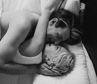 Loving cpuple laying on bed while embracing and kissing