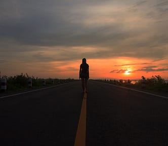 Girl walking alone at night on a deserted highway.