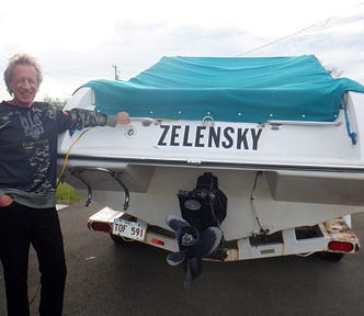 The author leaning against his boat with its name, “Zelensky,” on the stern