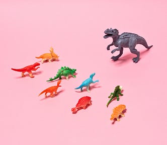 A photo of smaller dinosaur figurines in front of a T-rex figurine.