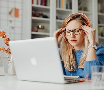 Woman in Blue Shirt Using Macbook Suffering a Headache