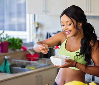 Woman eating strawberry in the kitchen. How to kill your sugar cravings