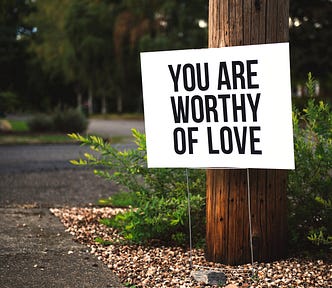 A signpost that says “You are worthy of love”.