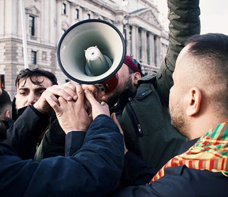 A man with a megaphone and his arm raised is surrounded by other men.