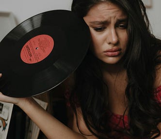 Woman holding vinyl record album, looking sad