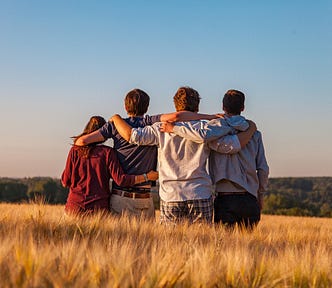 friends arm in arm looking out at a field.