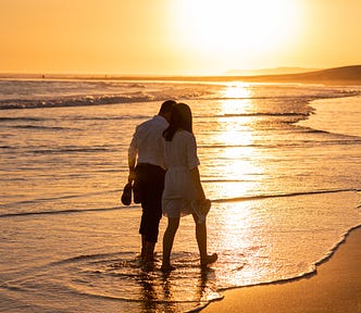 Second chance at love. A couple walk along a beach at sunset on a romantic date